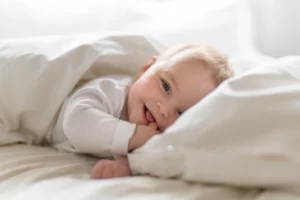 A cute baby smiling on a bed - her parents used acupuncture for fertility and were able to have her