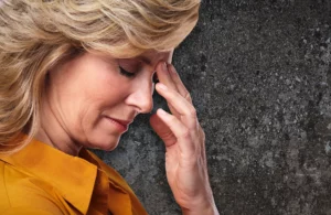 A blonde woman holding her forehead