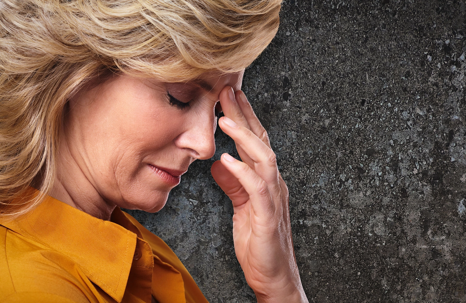 A blonde woman holding her forehead