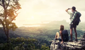 A man and woman resting at the top of a mountain looking at the view