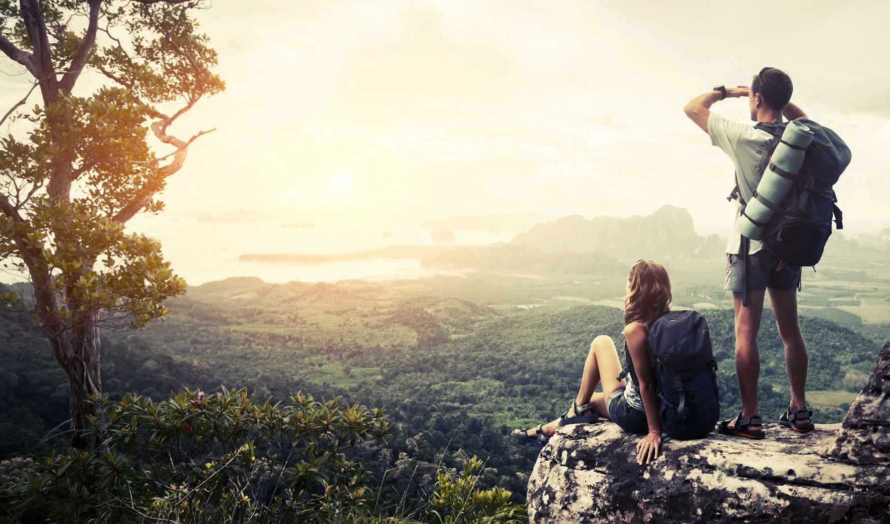 A man and woman resting at the top of a mountain looking at the view